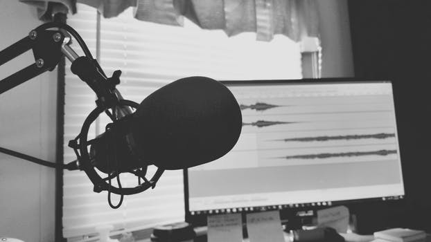 A black and white photo of a microphone capturing the best medical podcasts in front of a computer.